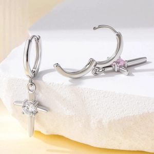Silver cross hoop earrings with pink and clear zircon stones on a marble block