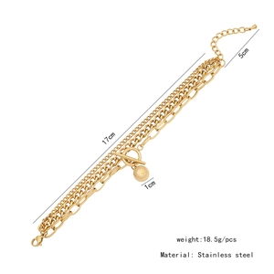Vue détaillée d'un bracelet triple chaîne en acier inoxydable doré avec breloque boule et fermoir T