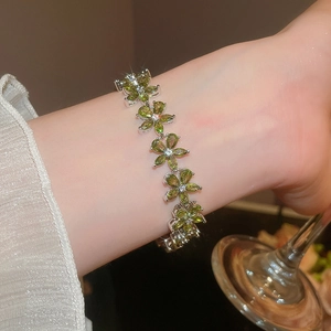 Close-up of elegant floral bracelet with green marquise stones worn at a social event