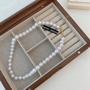 Detail of elegant pearl necklace with gold clasp inside a vintage wooden jewelry box