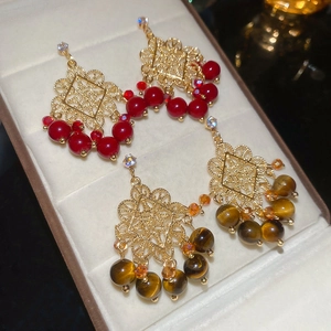 Detailed macro of vintage bohemian earrings with gold filigree and tiger eye stone beads
