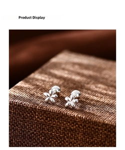 Vista macro de pendientes de flores de plata con cierre de rosca en tela marrón