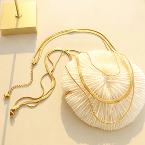 Gold double-layered herringbone and fine chain necklace with a heart pendant on white coral