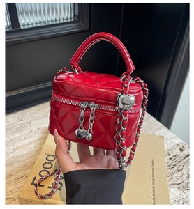 Detail of red quilted leather vanity box bag with heart zipper and chain strap