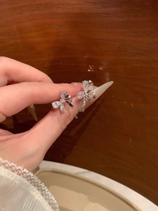Macro detail of silver bow earrings with sparkling cubic zirconia on a warm background
