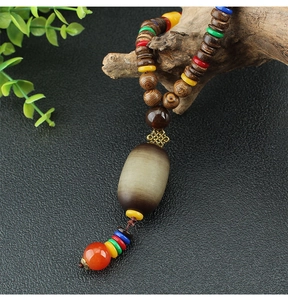 Detail of wooden beaded necklace with olive-shaped pendant on dark textured background