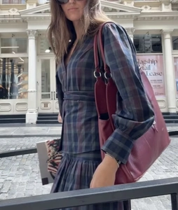 Dettaglio dell'abito vintage a quadri e borsa tote in pelle bordeaux in stile street