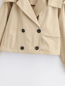 Detail of khaki cropped trench coat showing black double-breasted buttons and lapel collar