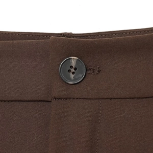 Pantaloni marroni in stile britannico con un dettaglio focalizzato sul bottone scuro