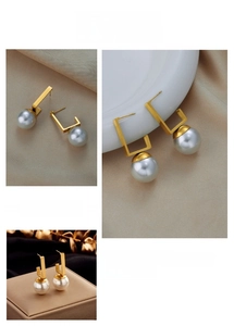 Detail of geometric gold frame pearl earrings on beige silk and leather jewelry box