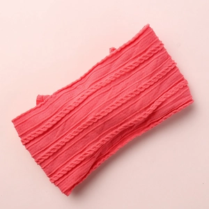 Detail showing coral pink cable knit texture on a wide nylon baby headband