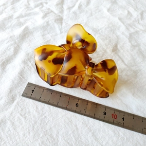 Close-up of amber tortoiseshell bow hair claw measured with ruler for size reference