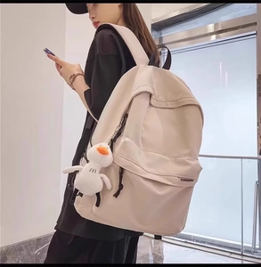 Dettaglio di zaino da viaggio beige con cerniere e accessorio peluche a forma di papera