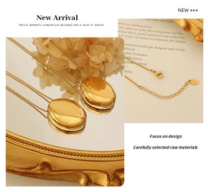 Close-up of gold oval pendant necklace showing the K18 hallmark on mirror-finish surface