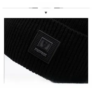 Detailed close-up of black ribbed knit beanie featuring a square logo rubber patch