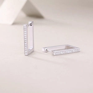 Close-up of silver rectangular hoop earrings with a row of inlaid cubic zirconia stones