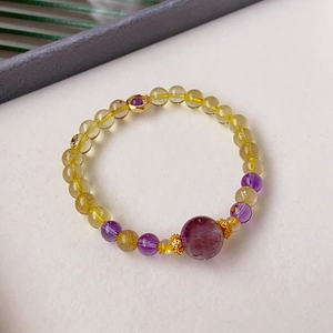 Detailed macro view of yellow rutilated quartz and amethyst beaded bracelet with gold accents