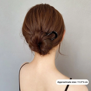 Close-up of a minimalist black U-shaped hair fork securing a bun hair accessory
