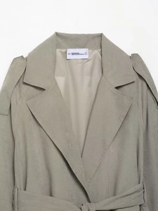Detail of grey-green suede jacket lapel with brand label and fine stitching texture