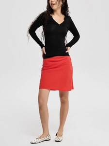 Close-up of a slim-fit black V-neck long-sleeve T-shirt paired with a red A-line skirt