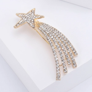 Detailed close-up of golden comet brooch with sparkling zircons on white cube