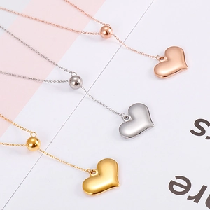 Three heart pendant necklaces in rose gold, silver and gold finishes on a soft pastel background