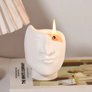 Detail of burning scented candle inside an abstract face sculpture ceramic mold