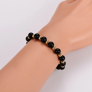 Tiger eye and obsidian beaded bracelet with gold accents worn on a model's wrist