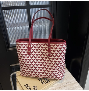 Detail of red and cream tote bag featuring heart pattern texture on marble surface