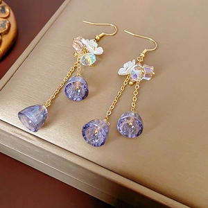 Detailed macro view of purple crystal flower earrings with elegant long golden tassels