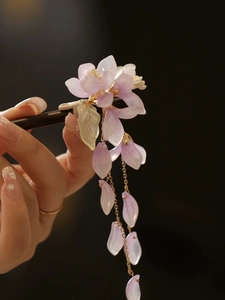 Detailansicht einer Haarnadel mit lila Begonienblüte, goldenen Quasten und Holzschaft