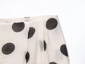 Detailed macro view of white chiffon fabric with large black polka dots and pleated texture