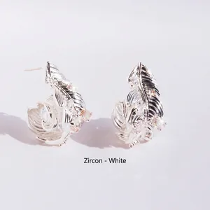 Elegant silver feather wrap earrings with sparkling white zircons on white background