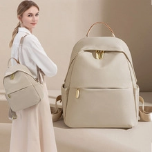 Detailed view of beige large nylon backpack with brown handles and metal buckle