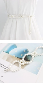 Detail showing elegant cream pearl waist chain with metal lobster clasp on a white dress