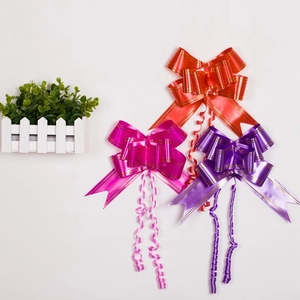Close-up of red, rose, and purple decorative gift bows with gold edges on white background