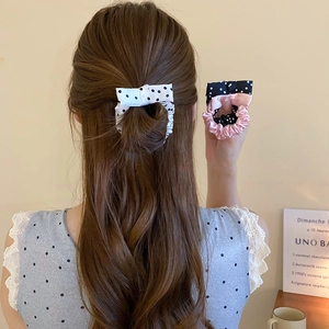 Detailed view of cream and black polka dot bow scrunchie with smooth satin texture