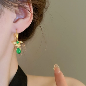 Detail of vintage teardrop earrings featuring golden leaf elements and emerald resin gems