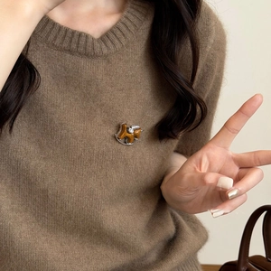 Detail einer beflockten Schaukelpferd-Brosche mit Diamanten auf einem Pullover