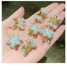Gros plan de petites pinces à cheveux fleur en perles dorées pour comparer la taille