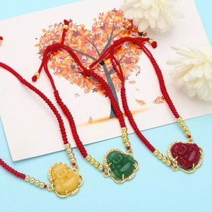 Detailed close-up of three Buddha pendants in red, green, and yellow on red cord bracelets
