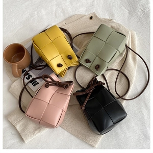 Flat lay of colorful hand-woven mini bucket bags in yellow, green, pink and black PU