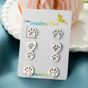 Set of four stainless steel animal paw stud earrings displayed on a white jewelry card