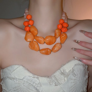 Close-up of double-layered orange acrylic beaded necklace with irregular stone patterns