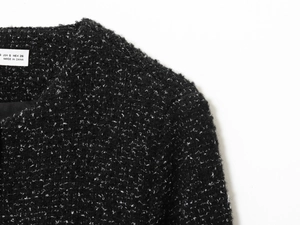 Détail de la texture en tweed noir et de l'étiquette de taille S sur le blazer femme