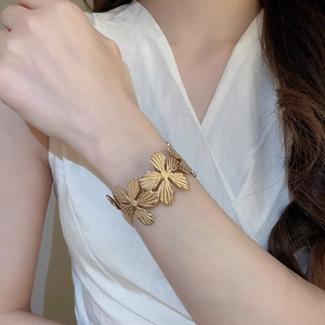 Dettaglio di un bracciale rigido dorato a fiori con petali vintage sulla modella