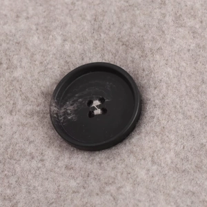 Detail of a black resin button on beige wool fabric showing premium sewing craftsmanship