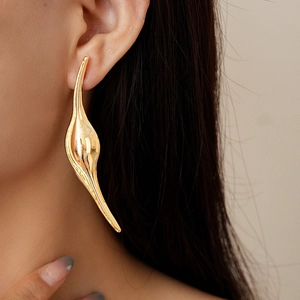 Detailed close-up of metallic curved leaf earrings with a polished golden mirror finish