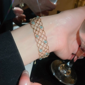Macro detail of golden beaded mesh bracelet with round blue crystal gemstones on wrist