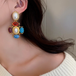Gros plan de boucles d'oreilles baroques vintage avec pierres colorées et perles sur modèle